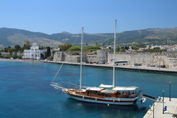 Fototapeta na wymiar Blick auf Stadtmauer von Kos Stadt mit Holzboot und blauem Himmel und Meer