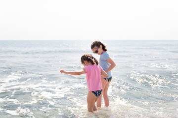 Sisters playing on the beach and holding hands.