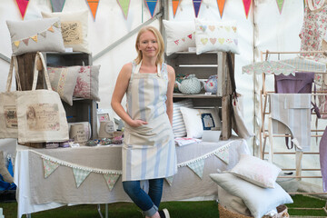 Female in apron front of shabby chic craft stall