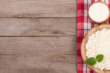 Obraz na płótnie Canvas Cottage cheese in a wooden bowl with sour cream on old wooden background with copy space for your text. Top view