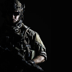 Elite member of US Army rangers in combat helmet and dark glasses. Studio shot, dark black...