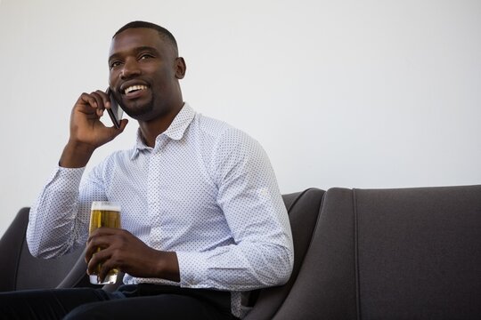 Businessman holding beer glass while talking on phone