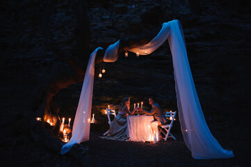 Romantic couple holding hands together over candlelight during romantic dinner outdoors