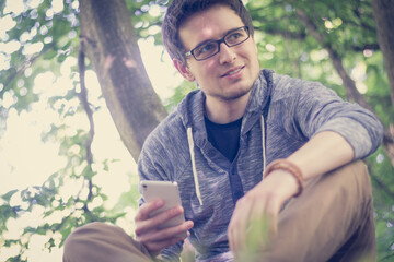 Junger Mann in Park, Blick aufs Smartphone
