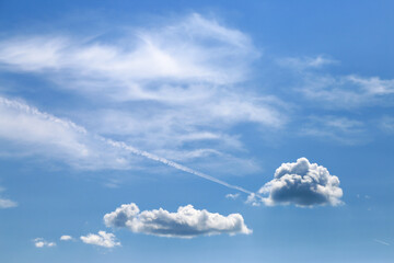 Blue sky with clouds and trail of plane