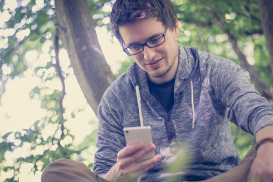 Junger Mann in Park, Blick aufs Smartphone