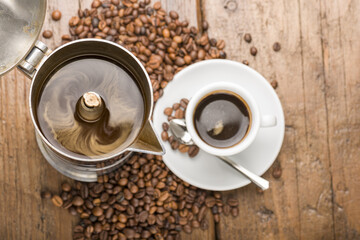 coffeepot and cup of coffee with coffee beans on wooden table