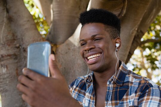 Young man with earphones listening to music on mobile phone