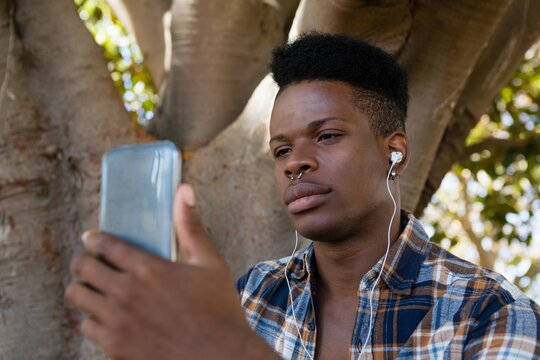 Young man with earphones listening to music on mobile phone
