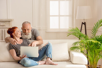 Beautiful happy mature couple using laptop together at home