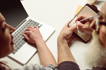 cropped shot of woman using laptop and man making notes