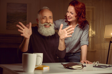 smiling red hair woman with mature man looking at camera with hands gesture