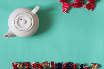 White teapot with sweets. Top view. Neutral background