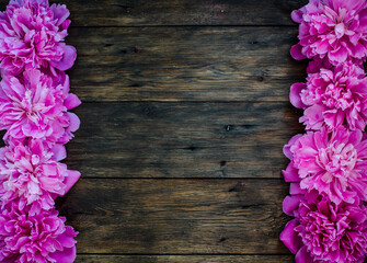 Floral frame with pink peonies flowers on wood background. Selective focus, place for text, top view