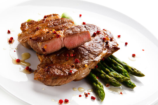 Grilled beefsteak with asparagus on white background