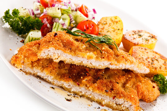 Fried pork chop with tomatoes and vegetable salad on white background