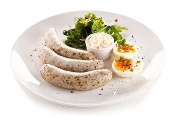 Home breakfast with white sausages and boiled eggs on white background