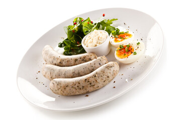 Home breakfast with white sausages and boiled eggs on white background