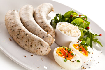 Home breakfast with white sausages and boiled eggs on white background