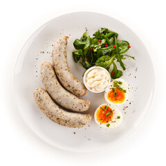 Home breakfast with white sausages and boiled eggs on white background