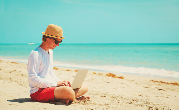 man working on laptop at tropical beach