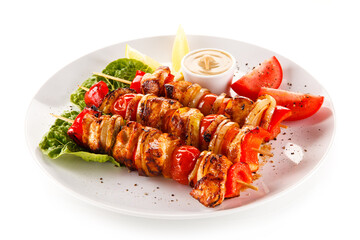 Roast meat with vegetables on stick on white background