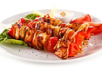 Roast meat with vegetables on stick on white background