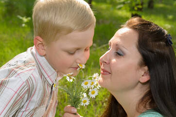 The boy gives flowers to his mother.
