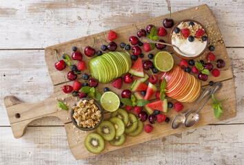 Fruit and yogurt for breakfast on a wooden cutting board.