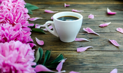 Morning spring coffee and pions flowers on a wooden background.