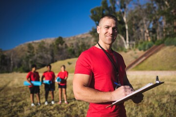 Trainer writing on clipboard in the boot camp