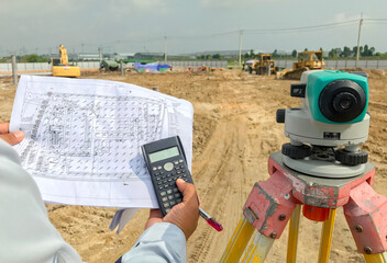 Surveyor equipment tacheometer or theodolite outdoors at construction site and construction worker in safety uniform - obrazy, fototapety, plakaty