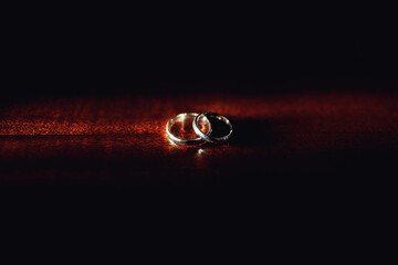 Sparkling wedding rings lie on wooden table
