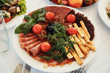 Sliced meat and cherrie tomatoes served on white dish