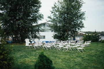 White chairs stand on a green lawn