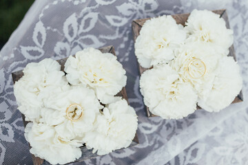 Wedding rings lie on white pinks on the table