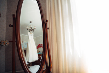 Reflection of wedding dress hanging on the lamp