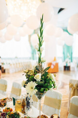 Little green bouquet in tall vase stands on dinner table