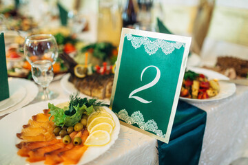 Number two written on green paper stands on dinner table