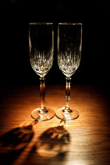 Crystal champagne flutes stand on wooden table