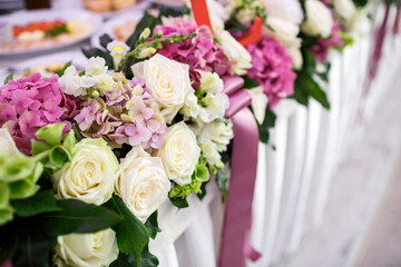 Garland of white roses and pink hydrangeas hangs from the table