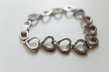 Silver bracelet made of hearts lies on white table