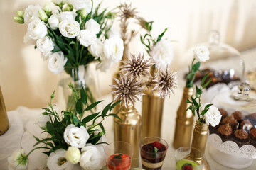 Golden bottles with white flowers stand among the sweets