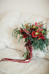 Red wedding bouquet stands on the white couch