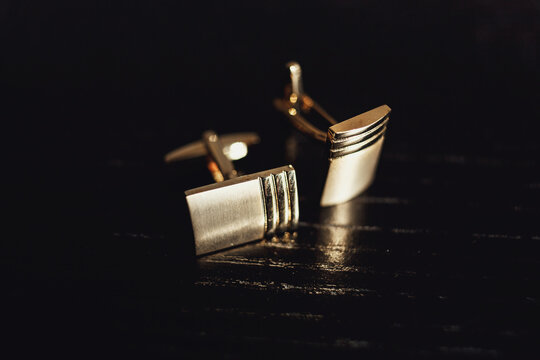Golden cufflinks lie on a black table