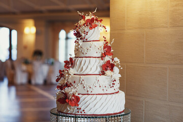 Tired wedding cake decorated with red flowers and icing