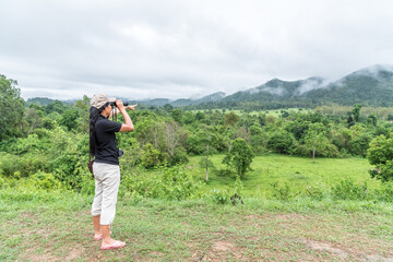Woman use binoculars for looking at the mountain.