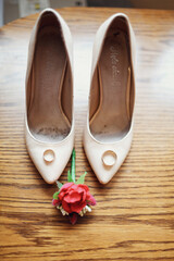 Golden wedding rings stand on beige shoes