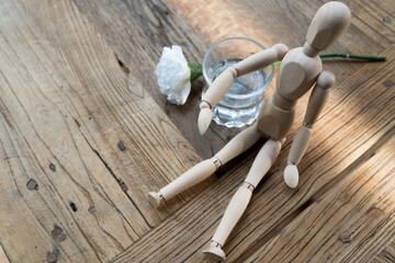 a wood man is sitting and put the arm on the glass of water