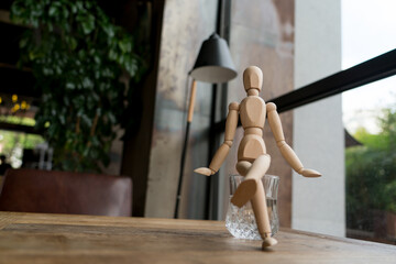 wood man is sitting on a glass of water